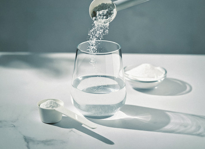 Kreatin-Pulver wird aus einem Messlöffel in ein Glas gegeben – zur Gewichtszunahme durch Kreatin