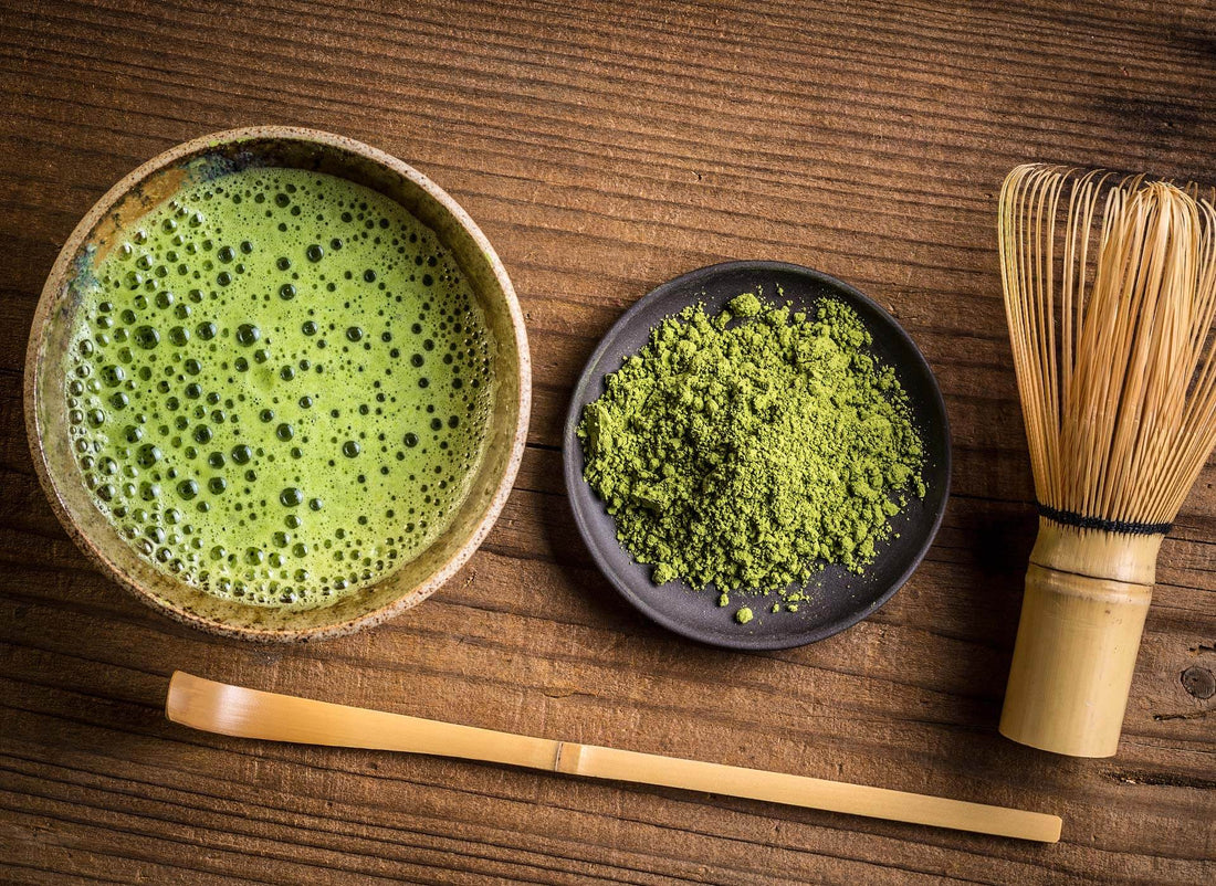 Matcha-Tee mit Bambusbesen und Matcha-Pulver auf einem Holztisch – traditionelle japanische Zubereitung