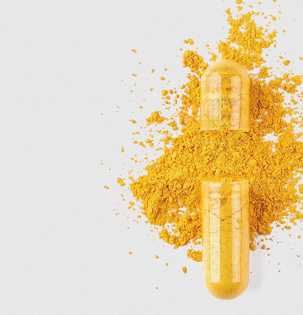 Geöffnete transparente Kapsel, aus der leuchtend gelbes Pulver auf einen hellen Hintergrund rieselt.